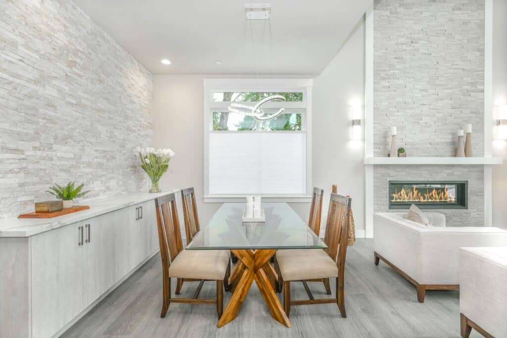 a beautifully remodeled living room and dining area with a modern stone fireplace