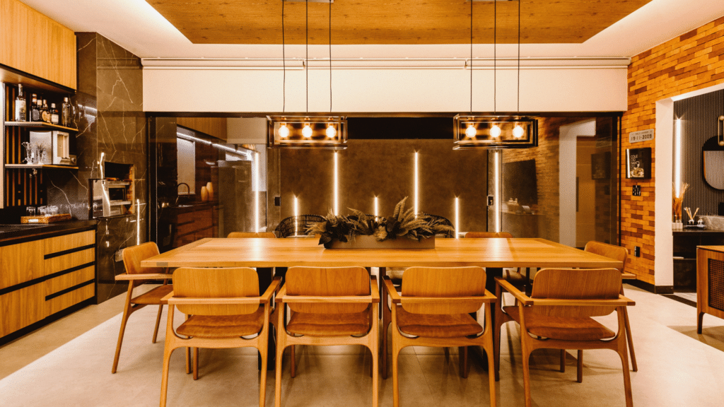 Warm-toned kitchen and dining area with wood cabinetry, black marble accents, and retro pendant lighting